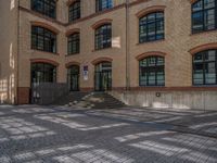 a brick courtyard has steps leading up to it, and a blue umbrella is on the ground