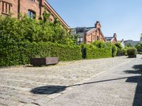 a brick street lined with brick benches next to tall buildings and greenery that line the sides