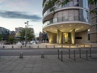 a building with a curved balcony that overlooks a square area, and parking space on the other side of the building