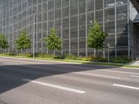 a road leading to a very large building surrounded by tall glass structures and trees in front