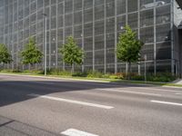 a road leading to a very large building surrounded by tall glass structures and trees in front