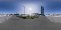 a street view with buildings in the background and the sun in the sky behind it