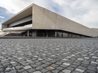 a large building with concrete floors is shown on a cobble stone road in front of it