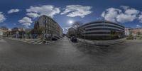 a 360 - view lens photo of an intersection in a town with cars parked on the road