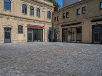 the sidewalk is paved with stones and has a bench in front of it, with no people inside