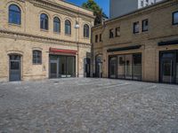 the sidewalk is paved with stones and has a bench in front of it, with no people inside