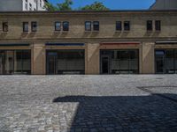 the sidewalk is paved with stones and has a bench in front of it, with no people inside