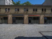 the sidewalk is paved with stones and has a bench in front of it, with no people inside