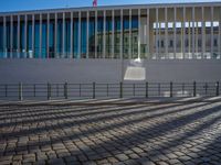 shadow of man on street in front of building and walkway with glass walls with large window