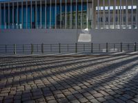 shadow of man on street in front of building and walkway with glass walls with large window