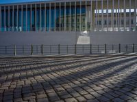 shadow of man on street in front of building and walkway with glass walls with large window