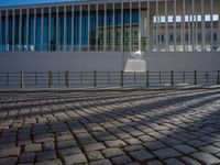 shadow of man on street in front of building and walkway with glass walls with large window