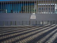 shadow of man on street in front of building and walkway with glass walls with large window