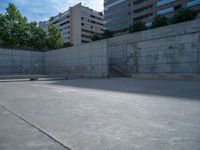 the empty parking lot in front of a wall with apartment buildings on it and a skateboarder on a ramp