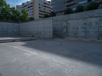 the empty parking lot in front of a wall with apartment buildings on it and a skateboarder on a ramp