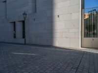 two people walking down an empty city street in an alley area with tall buildings in the background