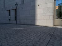 two people walking down an empty city street in an alley area with tall buildings in the background