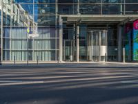 the sunlight reflects from several windows in a large building onto the street from outside the building