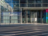 the sunlight reflects from several windows in a large building onto the street from outside the building