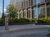 the side walk of a glass office building with concrete bricks and landscaping on each floor