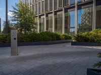 the side walk of a glass office building with concrete bricks and landscaping on each floor