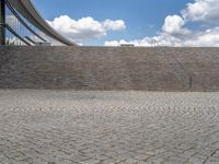 a person on a bike walking through a stone building entrance, in front of an enormous glass wall and stairs