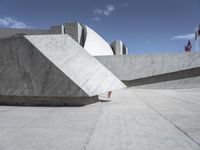 an empty cement wall in front of a red fire hydrant in concrete structure with other building on the other side