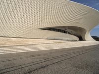 view of modern structure designed in white stone and grey stone tile with steps leading up to the building