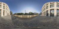 some kind of sphere on the ground in front of some buildings and blue sky behind