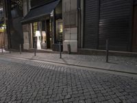 a woman walking down the street at night time, with her suitcase on the sidewalk