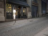 a woman walking down the street at night time, with her suitcase on the sidewalk