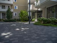 a paved brick street with red trash bins sitting in the middle and trees near to it