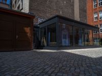 several plants sit in decorative concrete planters along the sidewalk of a building that is very modern