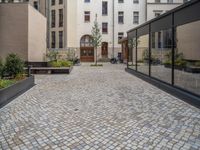 an empty parking lot with plants in the ground and on the side of the building, there is an enclosed area and windows