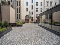 an empty parking lot with plants in the ground and on the side of the building, there is an enclosed area and windows