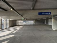 empty parking garage with only one floor and no roof, and an exit sign for pedestrians