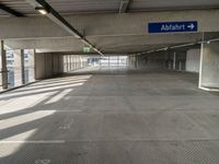 empty parking garage with only one floor and no roof, and an exit sign for pedestrians