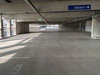 empty parking garage with only one floor and no roof, and an exit sign for pedestrians