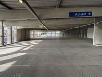 empty parking garage with only one floor and no roof, and an exit sign for pedestrians