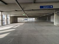 empty parking garage with only one floor and no roof, and an exit sign for pedestrians