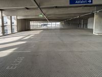 empty parking garage with only one floor and no roof, and an exit sign for pedestrians