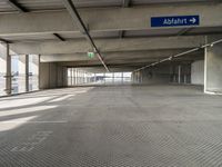 empty parking garage with only one floor and no roof, and an exit sign for pedestrians