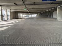 empty parking garage with only one floor and no roof, and an exit sign for pedestrians