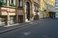 an empty street in the middle of a european city with multiple tall buildings on either side and several closed shutters behind