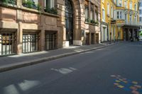 an empty street in the middle of a european city with multiple tall buildings on either side and several closed shutters behind