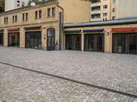 an empty street with small stores in the center of buildings in a european city by day