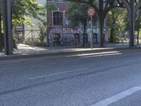 an empty city street, with a sign hanging off the side of it reads stop