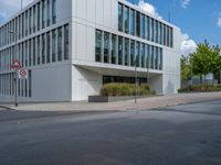 the building has a lot of glass windows on it, along with trees and bushes outside