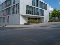 the building has a lot of glass windows on it, along with trees and bushes outside