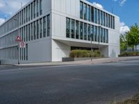 the building has a lot of glass windows on it, along with trees and bushes outside